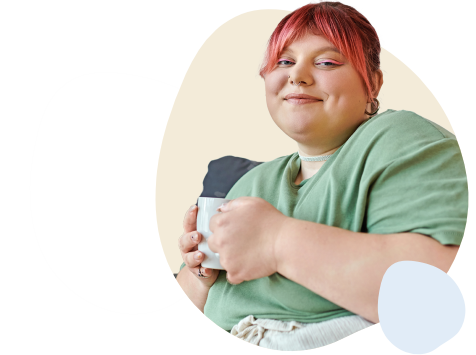 A young woman at the Distress Support Service holding a mug of tea and smiling at the camera