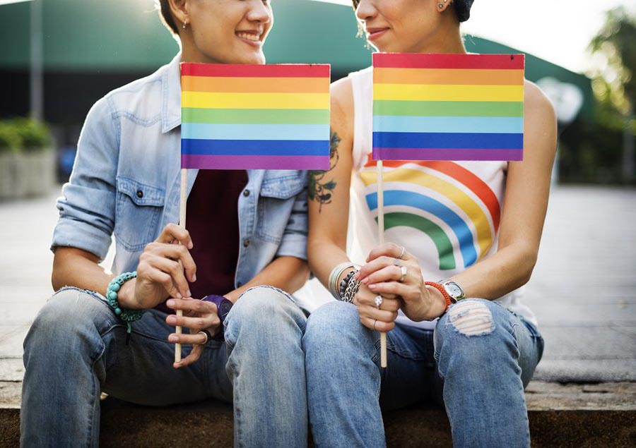 Two people holding LGBTIQ+ flags